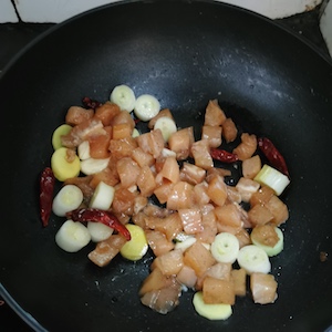 将腌制的鸡肉加入炒的大葱，姜，大蒜和干辣椒中。 静的宫保鸡丁