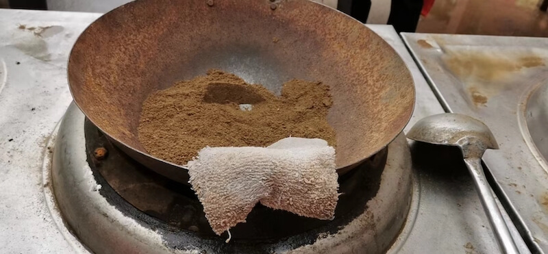 我们用旧铁锅练习。 The wok is large and heavy, and we add 4kg of sand to practice the techniques of wok cooking.