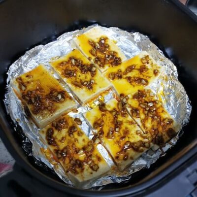 Place the tofu slices on aluminum foil and top with half of the chili oil sauce