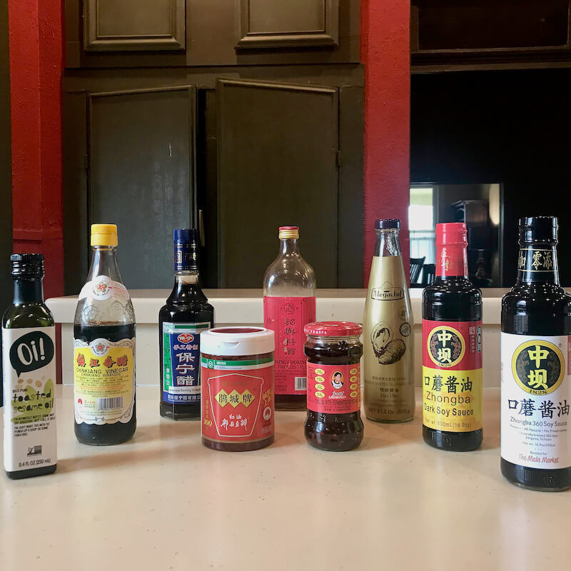 Essential sauces and oils: toasted sesame oil, vinegar (zhingkiang and baoning), Shaoxing wine, oyster sauce, Zhongba dark soy sauce, Zhongba light soy sauce, Pxian doubanjiang red bean paste, and Laoganma chili oil with black bean