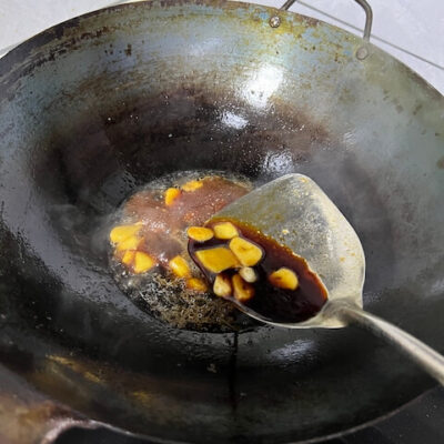 Heat the wok, add 15 ml oil, the ginger, and the garlic