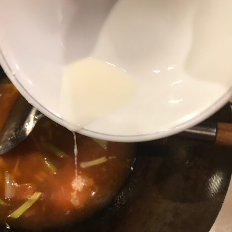 Thickening a sauce by adding thick starch, a few drops at a time, while stirring briskly.