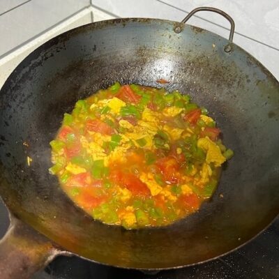 Simmer the scrambled egg, green pepper, and tomato with the garlic, soy sauce, and douban jiang to make a sauce for the noodles.