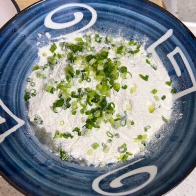 Add flour and chopped green onions to the eggs.