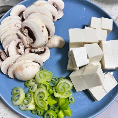 slice the mushroom, cube the tofu, and chop the green onions