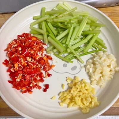 Prepare ingredients for Jing's Chinese Spicy Beef: sliced celery, chopped garlic, ginger and fresh xiaomila peppers.